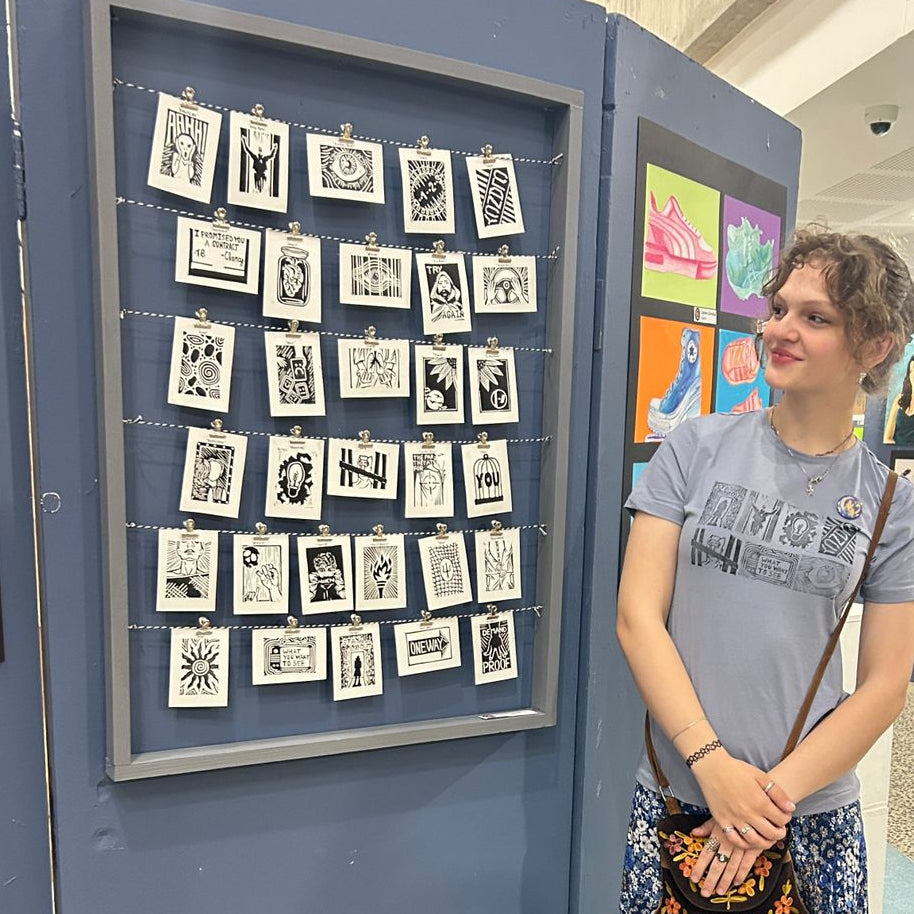 Woman standing by a display of black and white prints of an art series installation. 