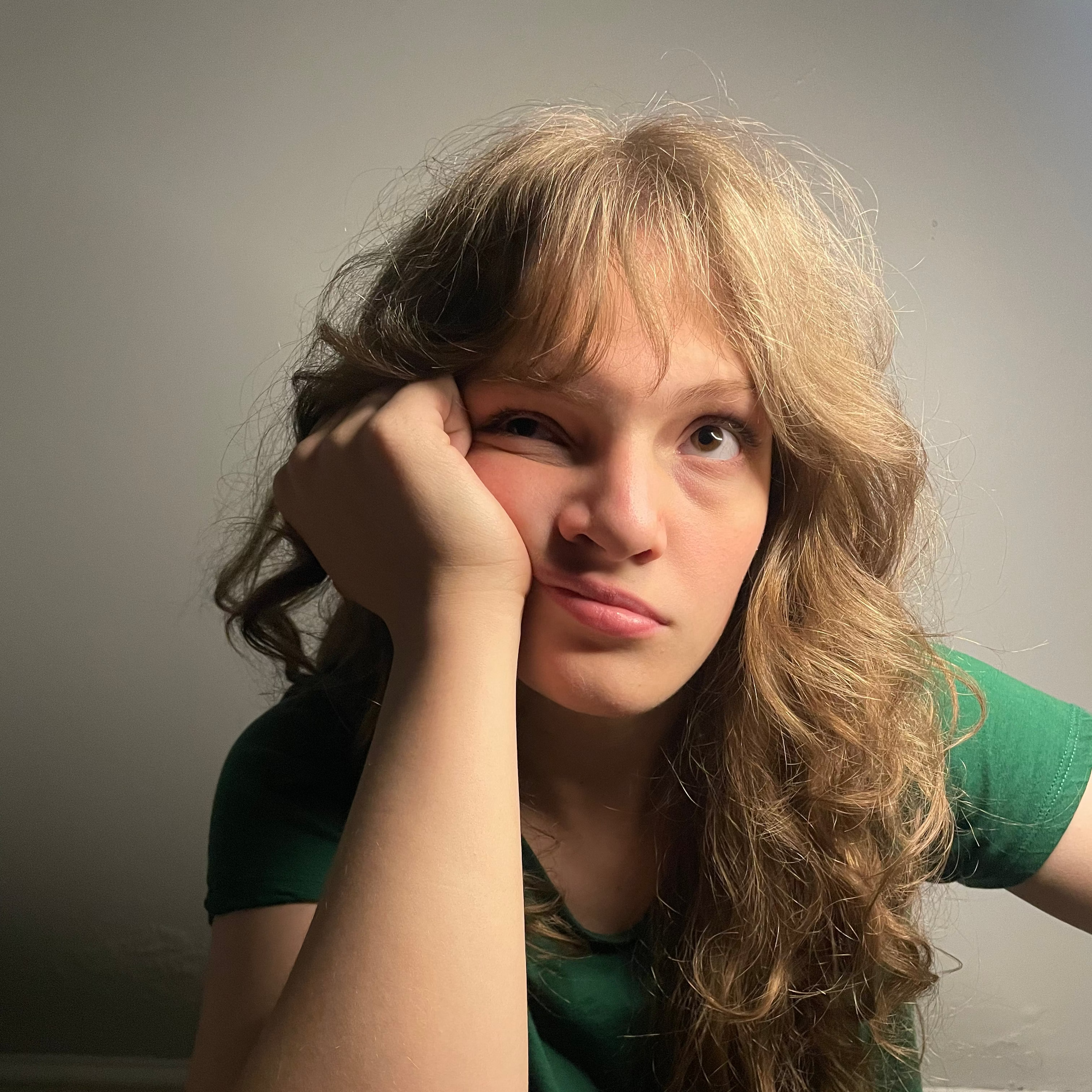 Woman with long hair wearing a green shirt against a plain background